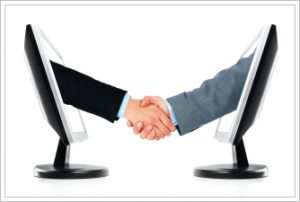 A business handshake between two computer monitors. Isolated on a white background.